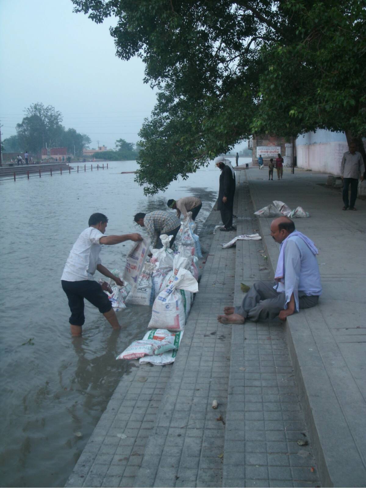 Fig. 4 : Photographie de l’immersion des cendres et des os des corps non identifiés brûlés dans les espaces funéraires de Delhi. Les sacs, remplis de restes humains, sont vidés dans le fleuve Gange par des prêtres funéraires et des travailleurs non religieux des espaces funéraires de la capitale indienne. Briand Antoine, Sati Ghat, Kankhal, 2017.